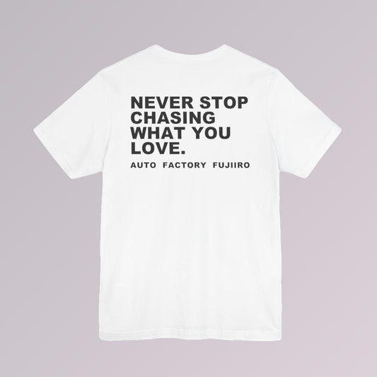 White — NEVER STOP CHASING WHAT YOU LOVE printed across the back of a white tee